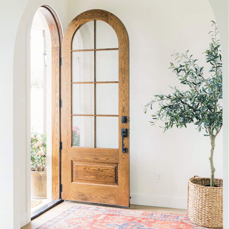 White oak arched entry door with glass panels in an Austin home